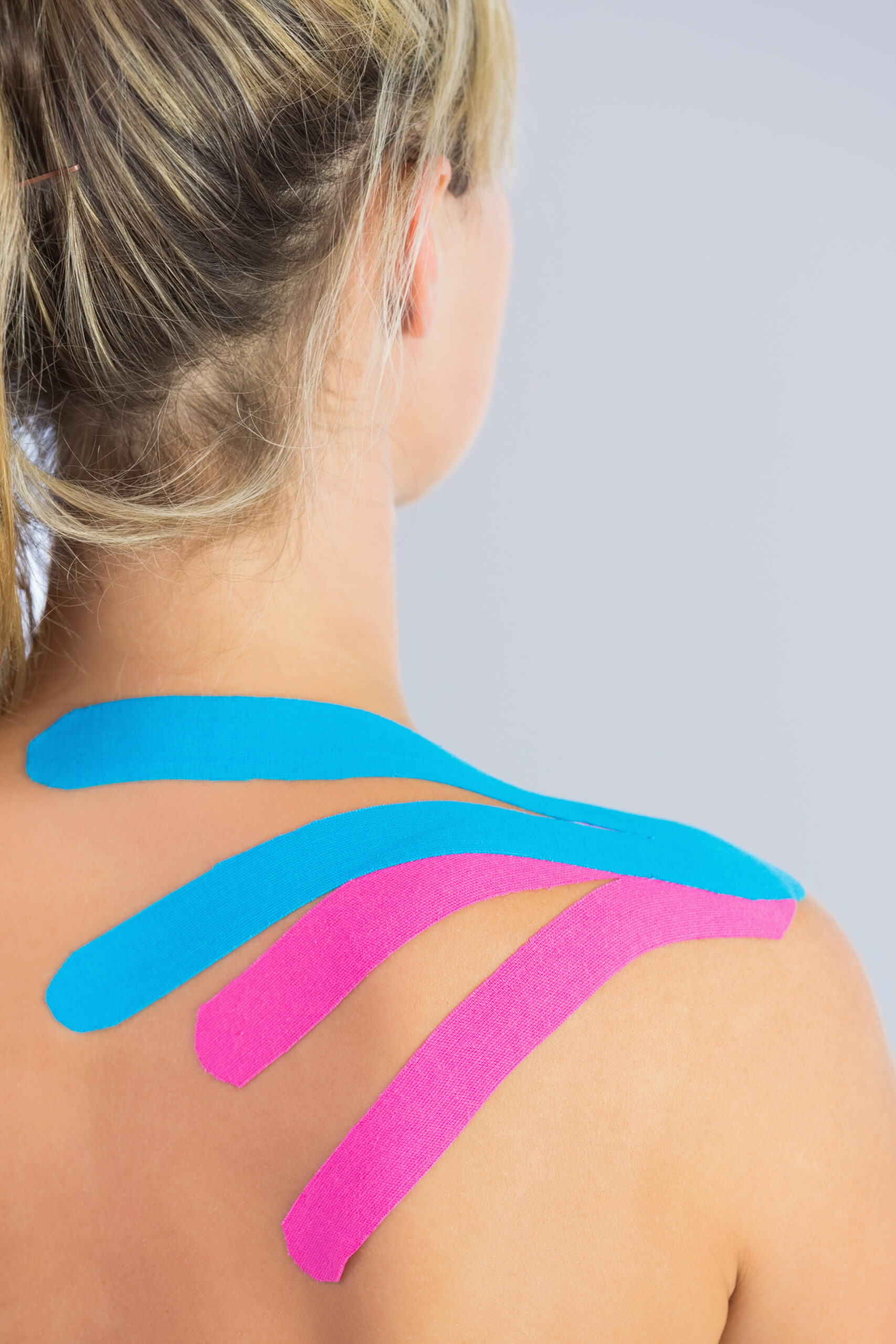 close-up-patients-shoulder-with-applied-pink-blue-kinesio-tape