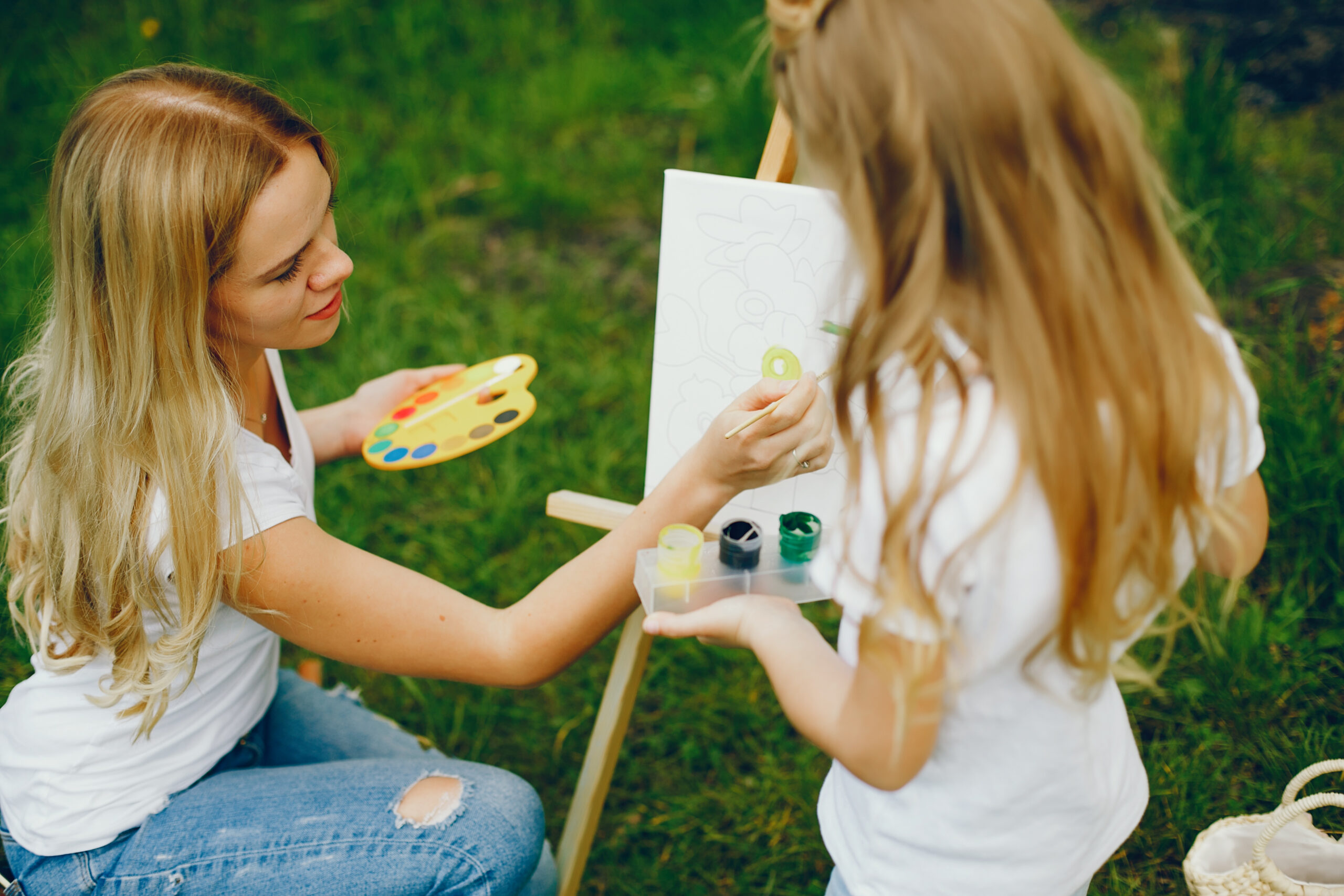 Beautiful mother with daughter. Family in a summer park. Little girl drawing