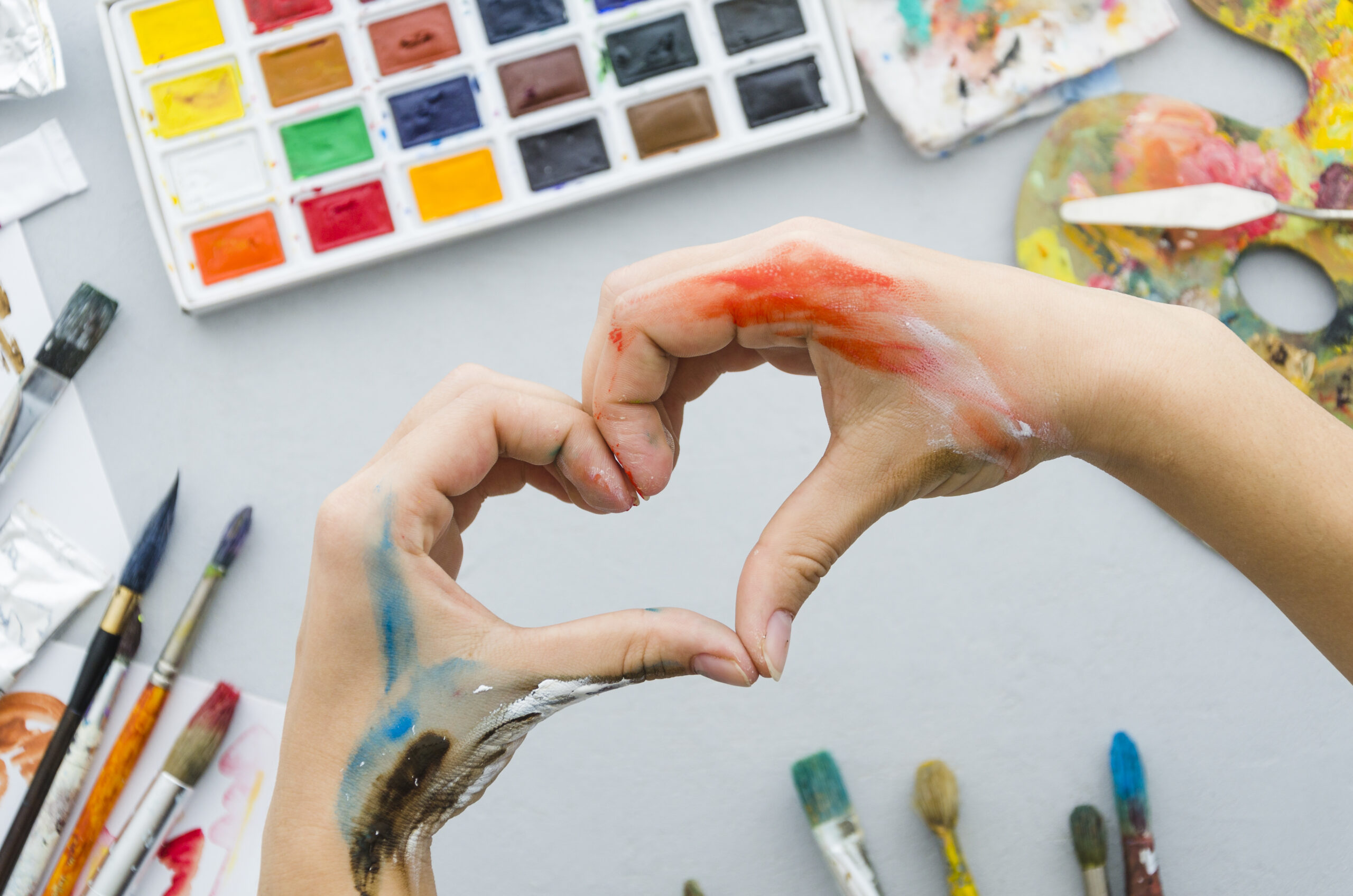 top-view-dirty-hands-making-heart-with-painting-materials